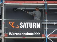 Saturn-Werbung, dahinter ein Arbeiter auf dem Gerüst