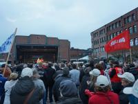 Kundgebungsteilnehmerinnen, DIE LINKE-Fahnen, im Hintergrund Bühne und Rathaus