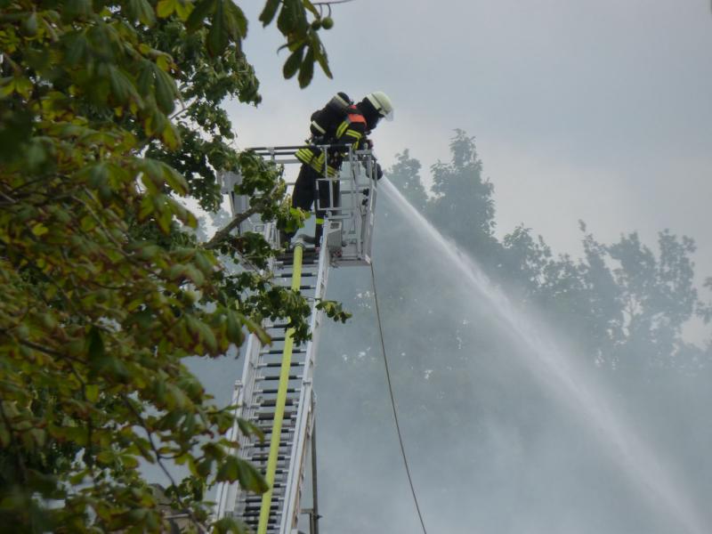 Feuerwehrmann, der von einer Drehleiter aus großer Höhe löscht