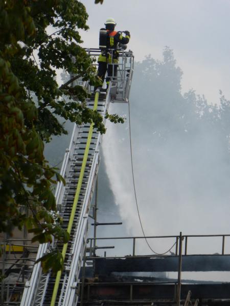 Feuerwehrmann, der von einer Drehleiter aus großer Höhe löscht